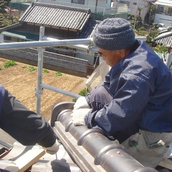 工事中：隅棟の鬼瓦取付、冠瓦を銅線にて固定。